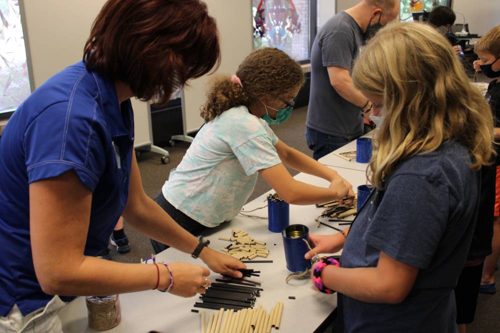 A teacher helps a student sort straws for her bee house